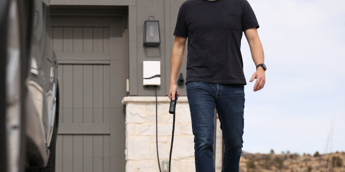 Man charging vehicle in driveway with Emporia EV charger