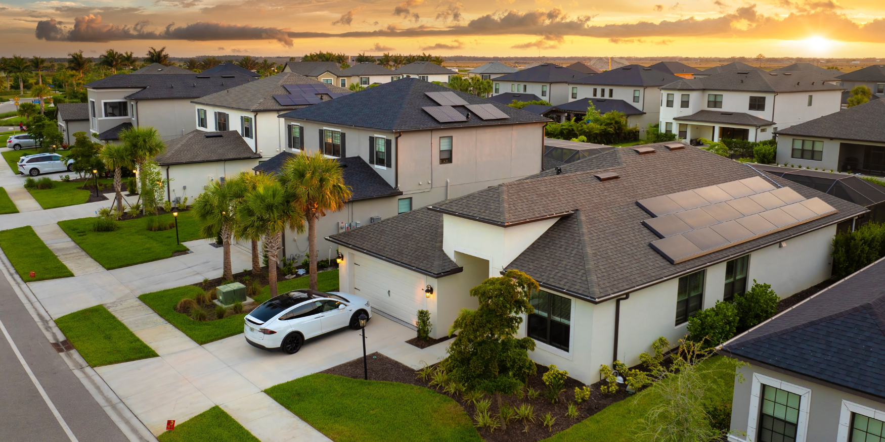 Four people on top of a roof installing solar panels with green tree background