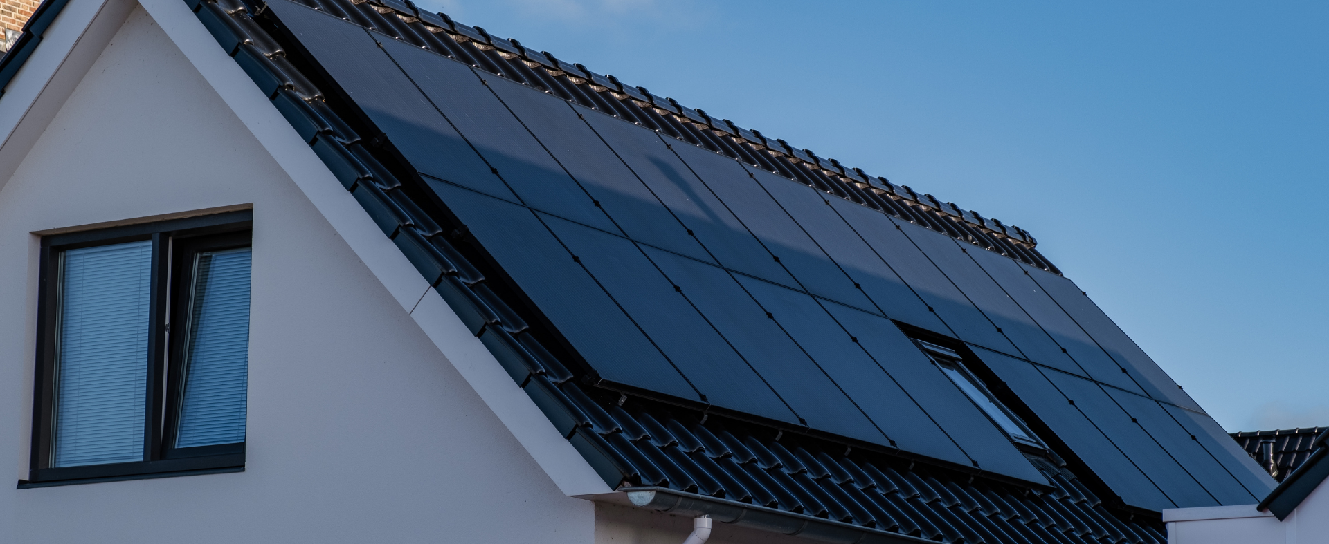 Sleek black solar panels on roof with sky background