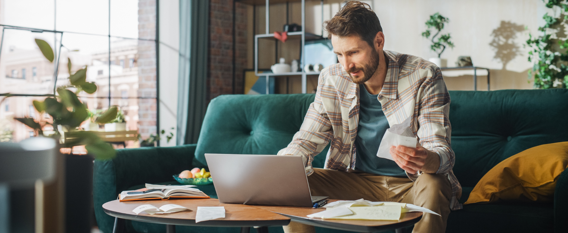 Person sitting on couch with laptop paying bills